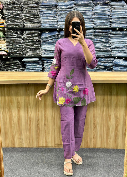 Woman wearing purple embroidered cotton kurti with pants standing in front of folded denim shelves