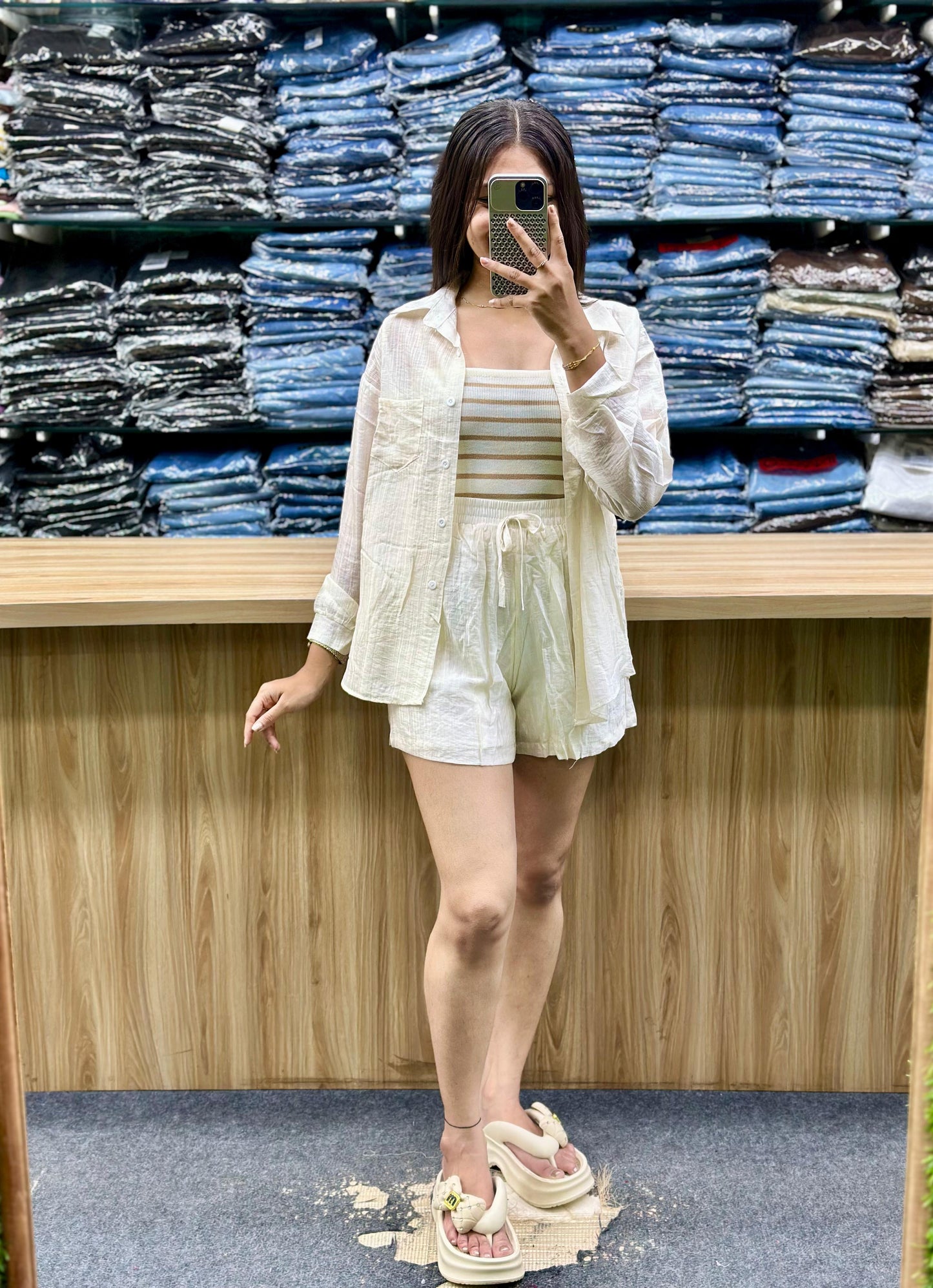 Woman wearing summer casual cotton outfits with white shirt and shorts posing in front of stacked denim jeans