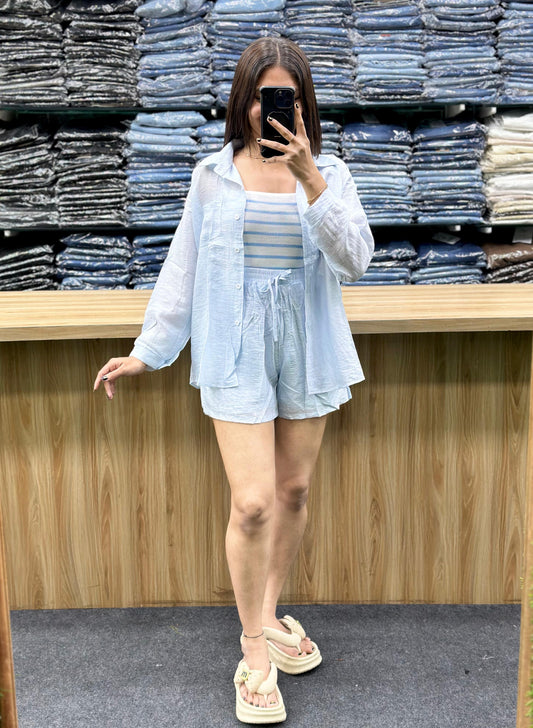 Woman wearing summer casual cotton outfits with light blue shorts and a matching shirt posing indoors