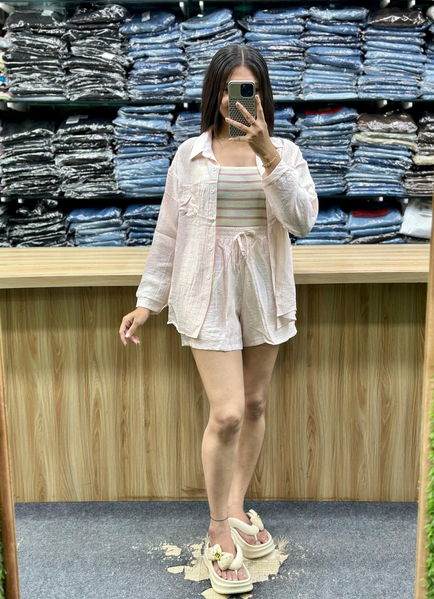 Woman wearing summer casual cotton outfits including a light pink shirt and shorts set in a clothing store