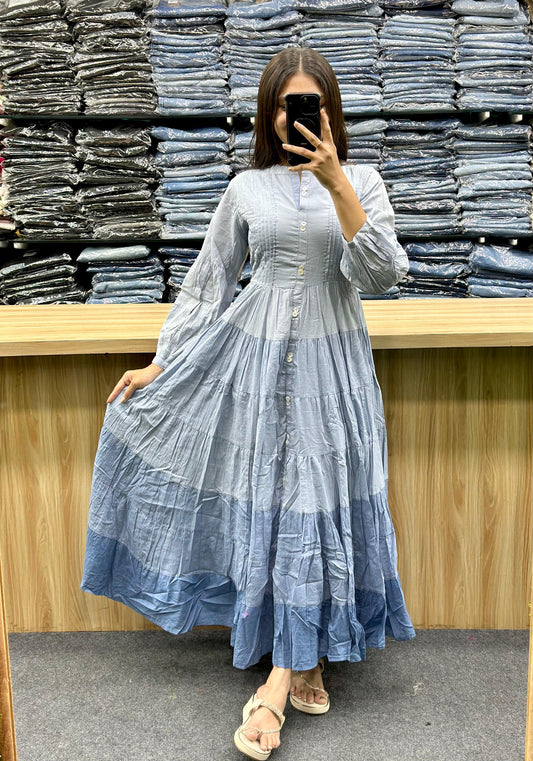 Woman wearing blue gradient ethnic cotton frock online style posing in front of stacked fabric at Vinayak Fashion
