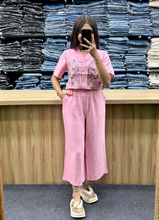 Woman wearing pink embroidered two-piece outfit with wide leg pants and short sleeve top at Vinayak Fashion store